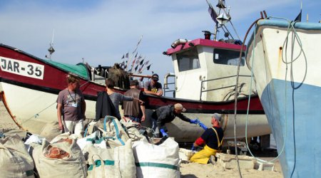 Fishermen in an exchange next to two beached vessels